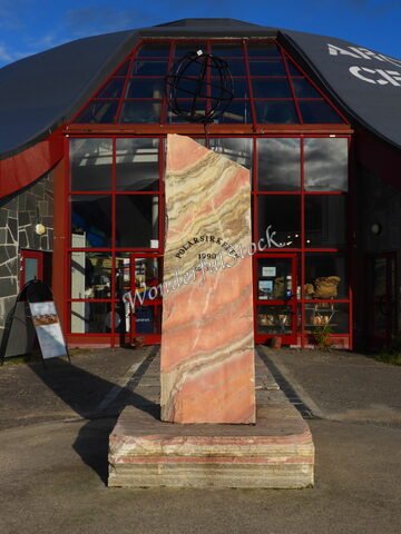Monument en marbre marqué "Polarsirkelen" devant un bâtiment, Norvège.