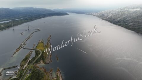 Vue aérienne du pont Helgeland en Norvège, avec des paysages montagneux et un fleuve calme.