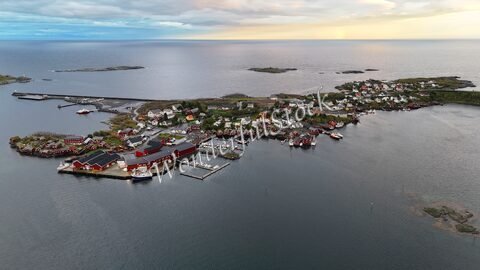 Village coloré au bord de l'eau en Norvège, avec des maisons blanches et rouges et des bateaux amarrés dans un environnement maritime.