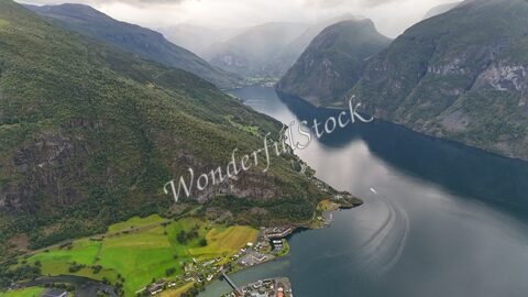Vue aérienne de Stegastein, Norvège, montrant des montagnes verdoyantes et un fjord calme.