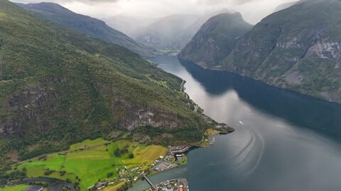 Vue aérienne de Stegastein, Norvège, montrant des montagnes verdoyantes et un fjord calme.