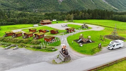 Vue aérienne d'un espace de loisirs à Trollstigen, Norvège, avec des cabanes en bois et une statue de troll.