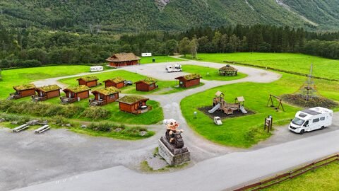 Vue aérienne d'un espace de loisirs à Trollstigen, Norvège, avec des cabanes en bois et une statue de troll.