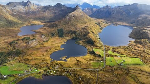 Vaste paysage de lacs et de montagnes en Norvège, avec des zones boisées et des terres agricoles visibles.