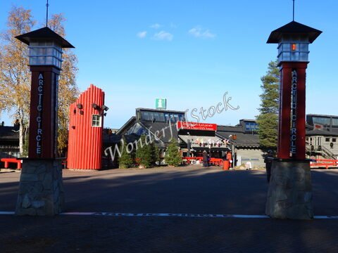 Entrée du cercle arctique à Rovaniemi, Finlande, avec des colonnes marquées et un bâtiment en arrière-plan.