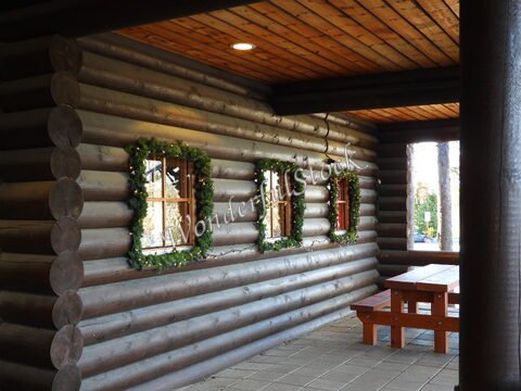 Mur en rondins avec fenêtres décorées de verdure et une table en bois, à Rovaniemi, Finlande.