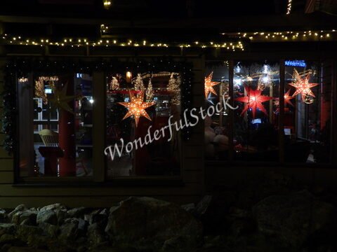 Étoiles décoratives illuminées dans une vitrine à Rovaniemi, Finlande, entourées de guirlandes lumineuses et de pierres.