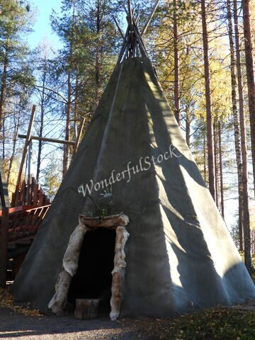 Tente en forme de cône avec une entrée en fourrure, entourée d'arbres, à Rovaniemi, Finlande.