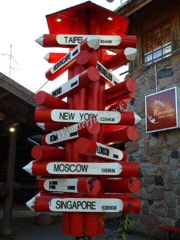 Panneau indicateur rouge avec des distances vers différentes villes à Rovaniemi, Finlande.