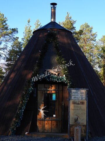 Une structure en bois avec un toit conique, décorée de verdure, à Rovaniemi, Finlande.