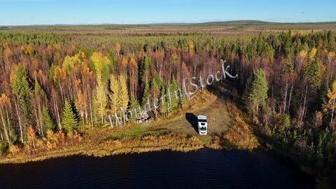 Forêt automnale et un véhicule près d'un plan d'eau en Finlande.