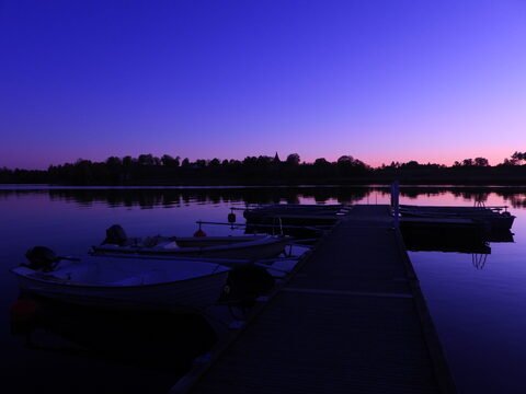 Bateaux amarrés sur un quai au bord d'un lac à Hammarskog, Suède, avec un ciel violet au crépuscule.