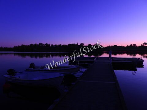 Bateaux amarrés sur un quai au bord d'un lac à Hammarskog, Suède, avec un ciel violet au crépuscule.
