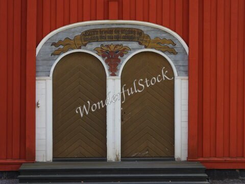 Porte en bois avec motifs colorés sur un bâtiment rouge à Kalix, Suède.