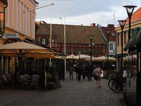 Ruelle pavée animée à Malmö, Suède, avec des terrasses de café et des bâtiments à façades colorées.