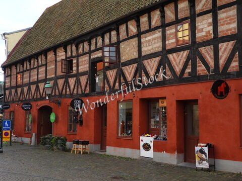 Bâtiment à colombages rouge et noir avec boutiques à Malmö, Suède, présentant des fenêtres et une lanterne.