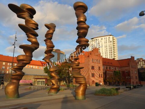 Des sculptures en bronze se dressent devant des bâtiments rouges à Malmö, Suède.