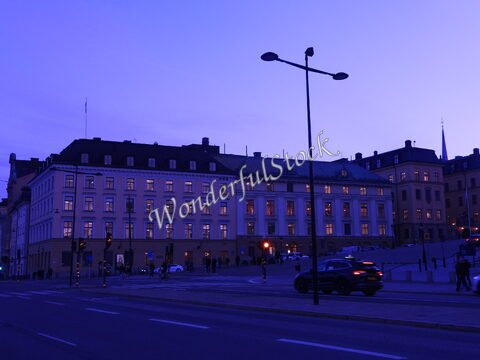 Bâtiment éclairé au crépuscule à Stockholm, Suède, avec des piétons et des voitures sur la route.