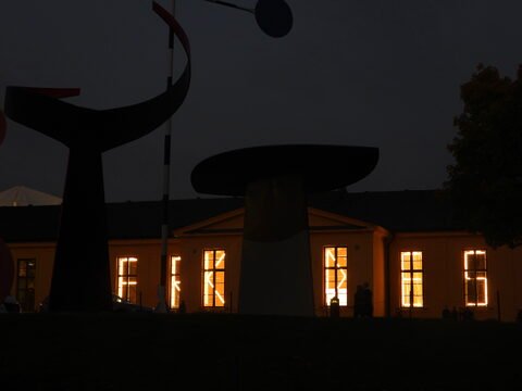 Sculptures modernes à Stockholm, Suède, avec des fenêtres illuminées d'un bâtiment en arrière-plan.