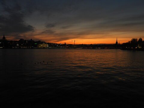 Coucher de soleil sur Stockholm, Suède, avec des silhouettes de bâtiments et des reflets sur l'eau.