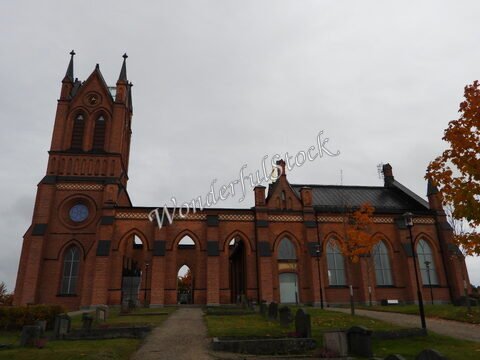 Église en briques rouges à Trönö, Suède, avec un clocher et des arbres aux feuillages automnaux.