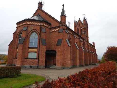 Église en briques rouges à Trönö, Suède, avec des fenêtres en arc et un toit à pignons.