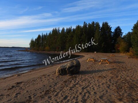 Plage de sable avec un grand rocher et des bancs en bois, Suède.