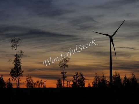 Éolienne silhouette au coucher de soleil, arbres en arrière-plan, Suède.