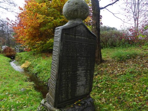 Monument en pierre avec inscriptions, entouré d'arbres et de feuillage, à Suède.