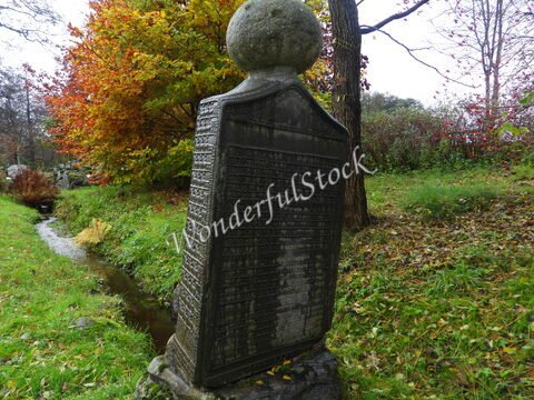 Monument en pierre avec inscriptions, entouré d'arbres et de feuillage, à Suède.