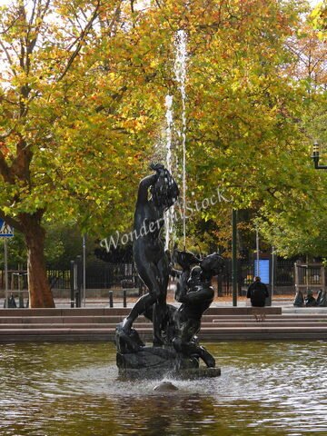 Fontaine avec sculptures au centre, entourée d'arbres aux feuilles dorées, à Malmö, Suède.