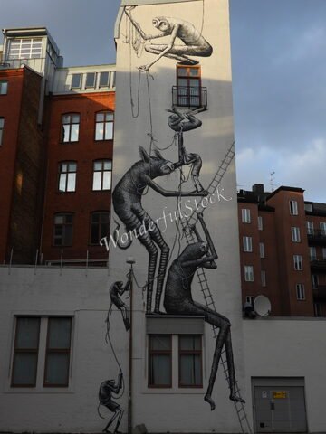 Mur décoré avec des personnages stylisés à Malmö, Suède, illustrant des figures grimpant et interagissant sur l'édifice.