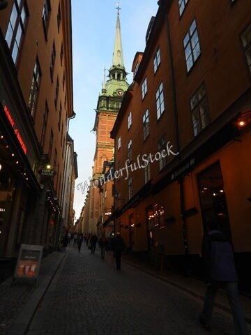 Rue pavée avec des bâtiments colorés et une tour d'église à Stockholm, Suède.