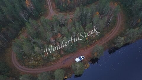 Véhicule garé près d'un lac entouré de forêts, en Suède.