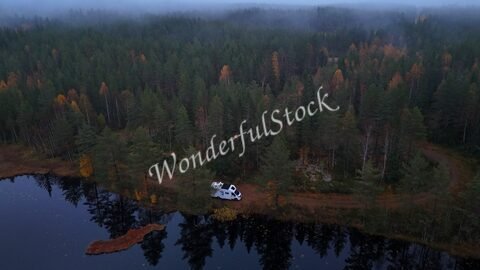 Un véhicule stationné près d'un lac entouré de forêts en Suède.