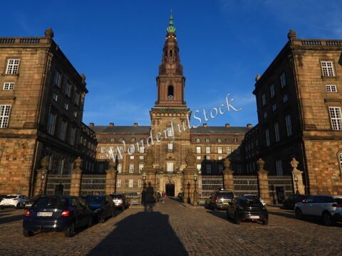 Palais avec une tour distinctive à Copenhague, Danemark, entouré de voitures sur un pavé.