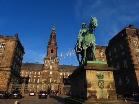 Statue équestre devant un bâtiment historique à Copenhague, Danemark, avec une tour pointue en arrière-plan.