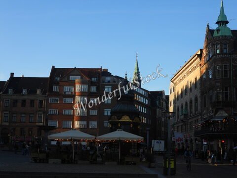 Bâtiments historiques et terrasses animées à Copenhague, Danemark, avec une horloge et un clocher visible.