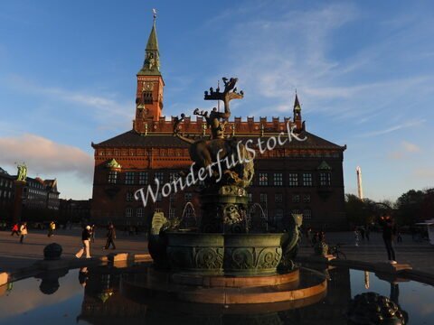 Fontaine ornée devant un bâtiment historique à Copenhague, Danemark, avec une horloge et des détails architecturaux distinctifs.