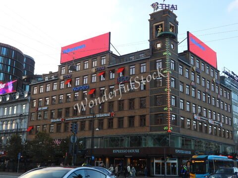 Bâtiment avec des enseignes commerciales à Copenhague, Danemark, incluant des logos visibles et une horloge extérieure.
