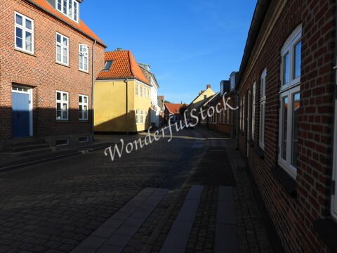 Rue pavée avec des maisons à colombages à Ribe, Danemark, sous un ciel bleu clair.