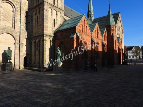 Édifice en briques avec statues à Ribe, Danemark, sous un ciel bleu.