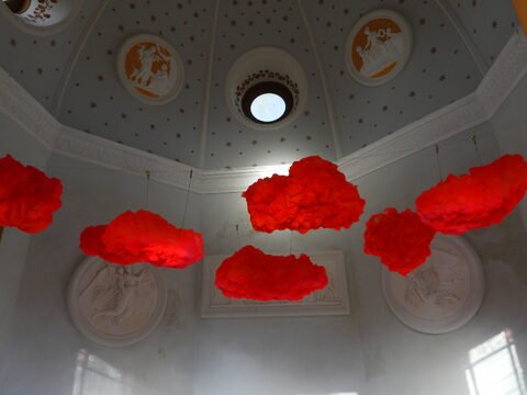 Nuages rouges suspendus dans une salle décorée à Ribe, Danemark, avec un plafond orné de motifs et de médaillons.