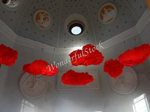 Nuages rouges suspendus dans une salle décorée à Ribe, Danemark, avec un plafond orné de motifs et de médaillons.