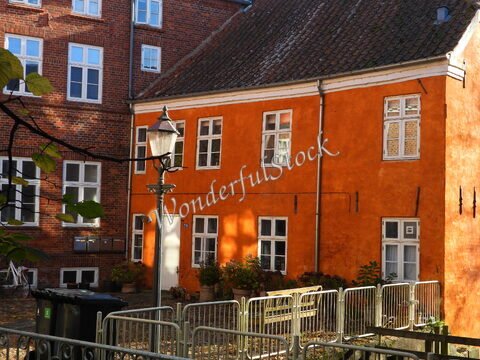 Maison aux murs orange et briques, avec lampadaire et plantes, à Ribe, Danemark.