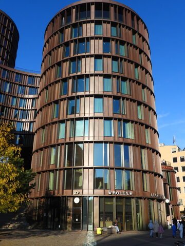 Immeuble moderne à Copenhague, Danemark, avec des façades en verre et des boutiques visibles au rez-de-chaussée.