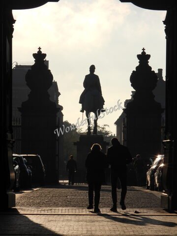 Silhouette d'une statue équestre à Copenhague, Danemark, avec des passants et des colonnes ornées en arrière-plan.