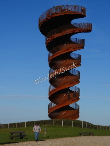Tour en spirale en métal à Marsk, Danemark, avec un visiteur au premier plan et un ciel dégagé.