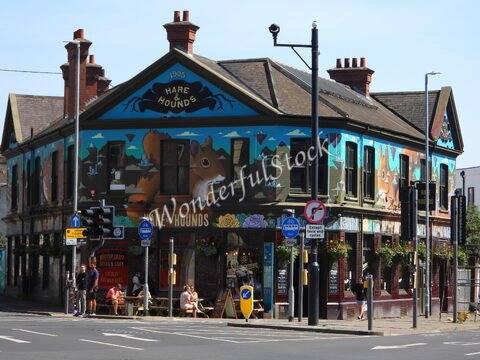 Un pub coloré avec une fresque murale à Brighton, en Angleterre, où des personnes s'asseyent à des tables en extérieur.