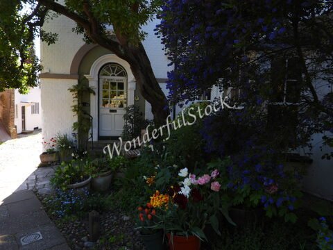 Maison avec un jardin fleuri à Canterbury, Angleterre, entourée d'arbres et de fleurs colorées.